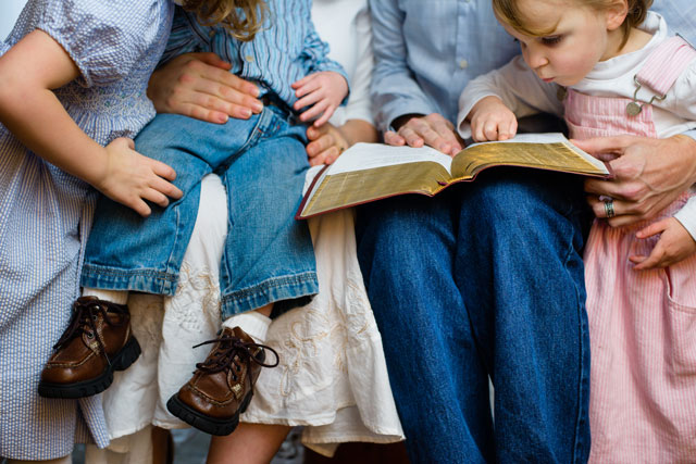 Parents reading Bible to children
